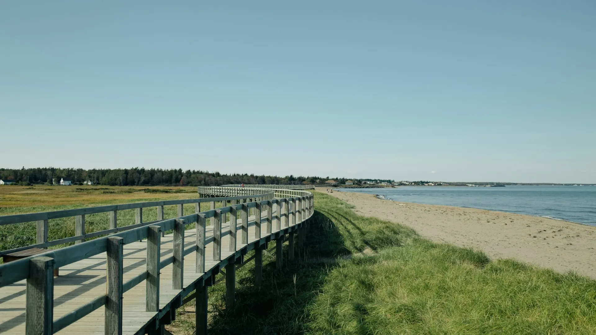 A wooden boardwalk running along a sandy beach